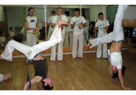 ŞI LUPTĂ, ŞI CÂNTĂ... Cu instrumente muzicale specifice Braziliei, luptătorii capoeira învaţă arte marţiale. Scopul lor, însă, nu este să se lupte, ci să se relaxeze şi să-şi pună la punct condiţia fizică...